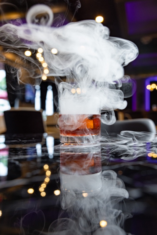 A smoking cocktail on a dark bar