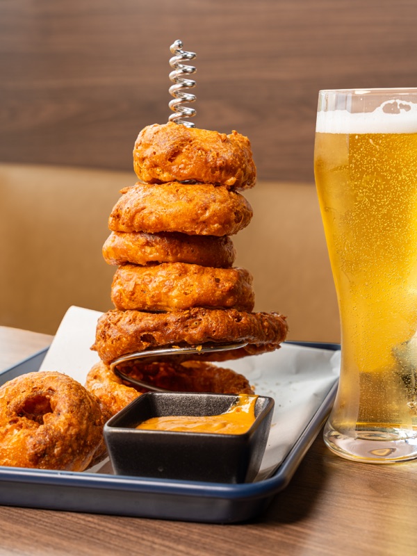 A tower of onion rings beside a beer
