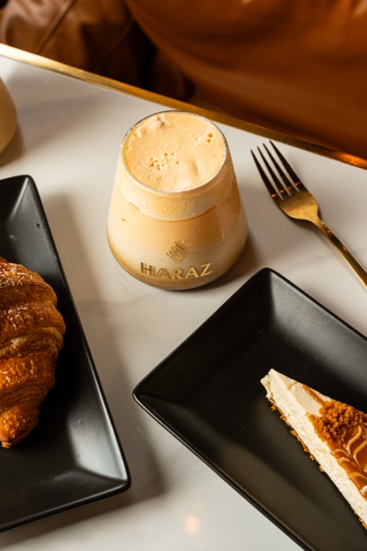 A croissant, iced latte and cheesecake on a cafe table
