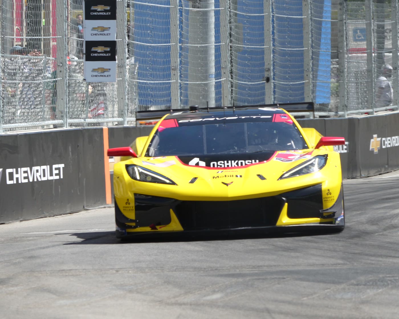 A yellow race car with a mirror finish coming through a corner