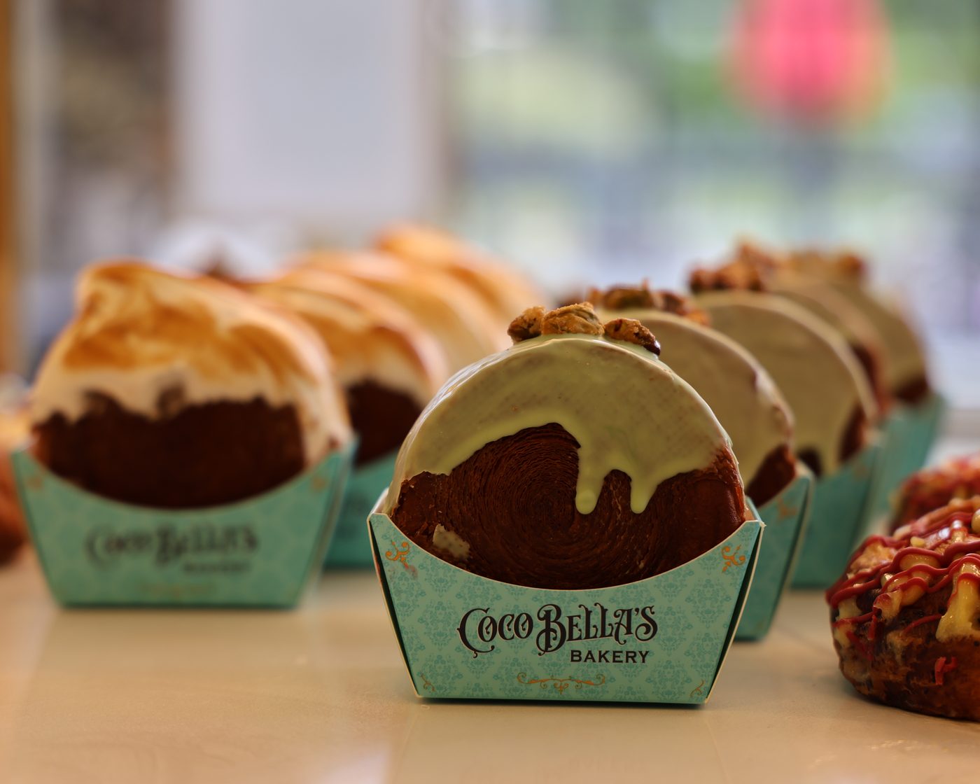 A chocolate pastry in a branded paper boat on a bakery counter
